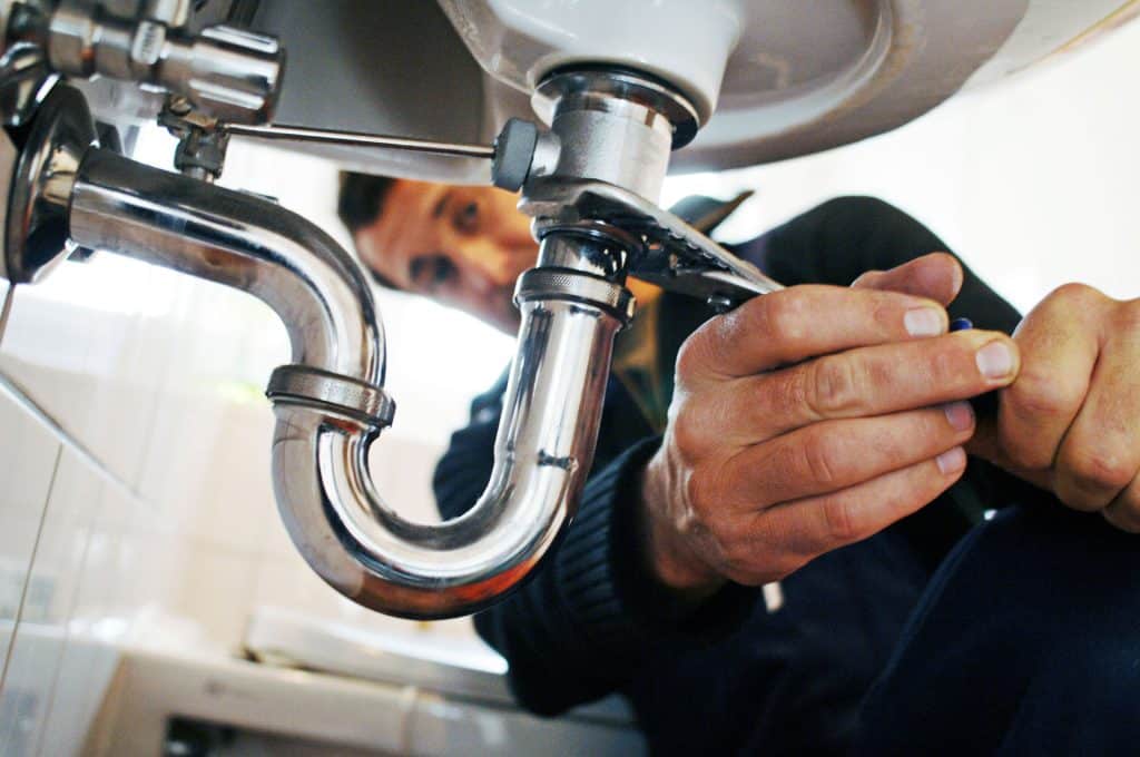 A professional plumber repairing sink pipes