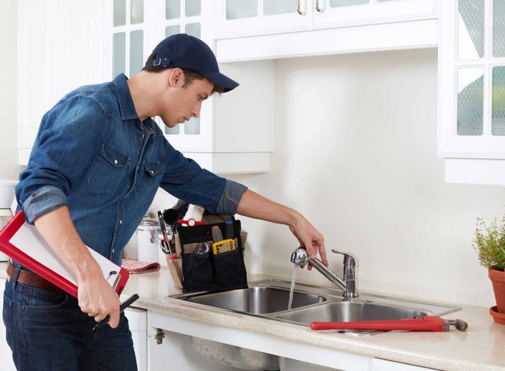 Home's kitchen sink being repaired by a professional plumber